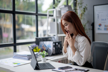 Obraz premium A woman is sitting at a desk with a laptop and a cell phone