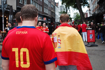 Selective Spanish flag and spanish football shirt are wear by football fan who walk in old town. 