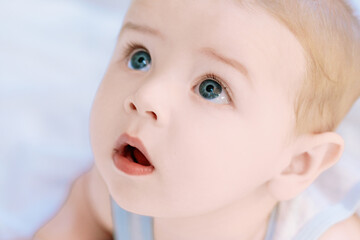 Adorable baby boy lying on back and looking up with open mouth
