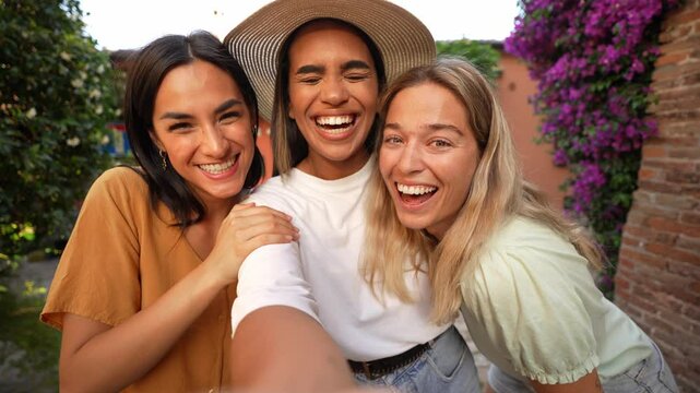 Three multiracial girls taking video selfie outside - Happy group of young women enjoying vacation walking in city street - Technology and summertime holidays concept - 4K video