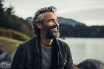 Portrait of a happy man in his 40s wearing a trendy sunglasses isolated on serene lakeside view