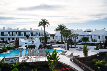 Fototapeta premium Hotel floors with a swimming pool with slides in the center with palm trees and a blue sky.