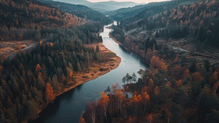 Fototapeta premium A winding river flowing towards a hilly lake surrounded by forests