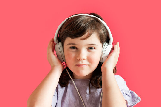 Young girl wearing headphones on a red background
