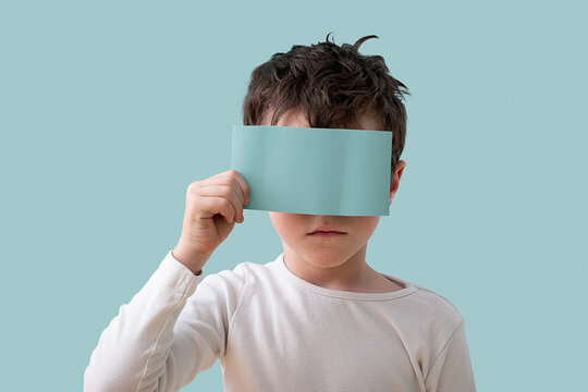 Young boy holding a blue card over his face in studio