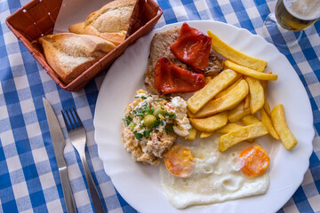 Plato combinado con patatas, huevos fritos, chuleta y ensalada