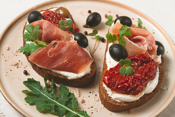 sandwiches with cheese and prosciutto, dried tomatoes and olives, breakfast on a plate,