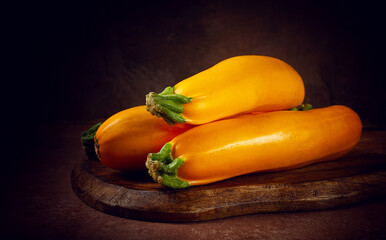 yellow zucchini, fresh, raw, on a wooden chopping board, no people,