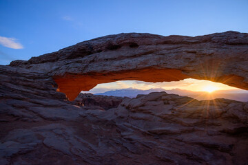 Breathtaking view of sunrise at Mesa Arch in Canyonlands National Park, Utah. The sun&rsquo;s rays illuminate the arch and the rugged landscape, showcasing the beauty of the red rock and morning light - USA