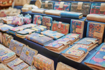 Detail of the wallets, purses and bags handmade from natural cork and decorated with colorful motifs that are sold at a stall at an artisan market.