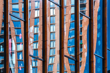 An abstract image capturing reflections of building windows in distorted glass, creating a modern art piece that highlights urban development, architecture, and contemporary artistic expression.