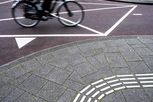 This image captures a cyclist in motion on a curved path with geometric patterns, representing the dynamic movement and rhythm of urban life and the blend of human activity with modern design.