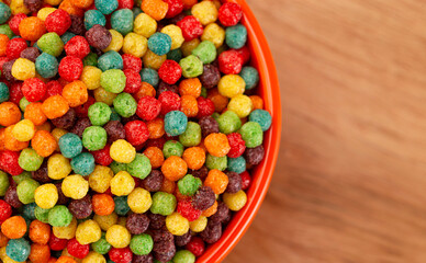 A Bowl of Small Ball Shaped Fruit Flavored Breakfast Cereal on a Wooden Kitchen Table