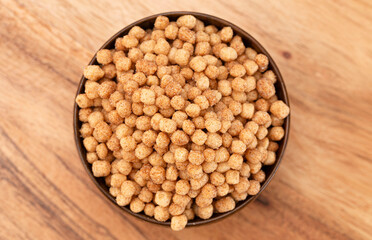 A Bowl of Small Ball Shaped Cinnamon Toast Flavored Breakfast Cereal on a Wooden Kitchen Table