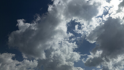 Fototapeta premium A plane flies in the sky surrounded by numerous clouds, while another plane is visible through the dense cloud cover in front
