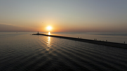 Obraz premium A sunset scene over a sizable water body features a pier anchored centrally