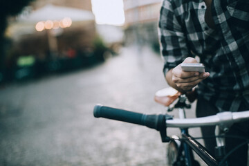 Man using smartphone while riding bicycle in city