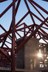 Geometric composition of red metal beams and a blue crane in a modern construction against a clear...