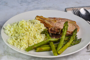 pork chop  with a side of rice and asparagus