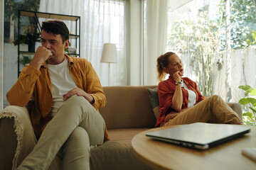 Young couple sitting on sofa opposite each other, they having an argument with each other