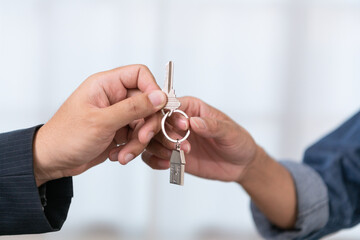 A real estate agent handing over the keys and signing the contract for a new home to a smiling young couple The couple was happy to buy a home and own a new home.