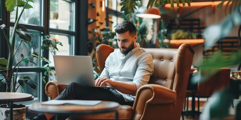 A man is sitting in a chair with a laptop on his lap