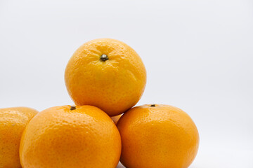 Mandarin oranges stacked together with a white background. Organic and fresh ripe fruit for healthy eating. Close-up ripe orange fruit texture with copy space. Still-life fruit with white background.