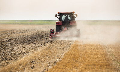 Naklejka premium Tractor preparing land with seedbed cultivator.