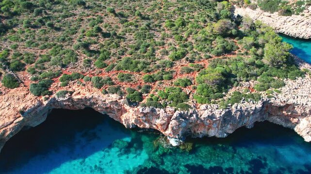 4K Aerial Drone video of the most incredible turquoise blue water color with a unique rocky cliff formation and boats anchored in on a beautiful summer sunny day, Cala Varques secluded beach, Mallorca