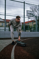 Young man enjoying an active lifestyle, pursuing his hobby skateboarding on a sports track in the park.