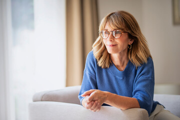 Mid aged woman relaxing in an armchair in her modern home
