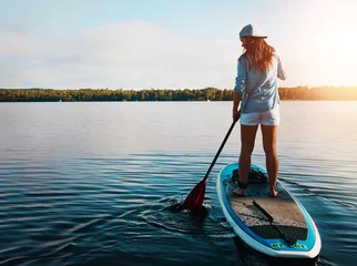 Fototapeten Back, woman and lake for paddleboard on holiday with adventure, recreation and fun in Bali. Female person, explore and travel for summer vacation, journey and break to relax with fitness activity © ReeseArcurs/peopleimages.com