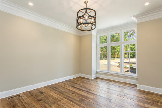 Empty Dining Room with Wooden Floor, Large Windows, and A Modern Chandelier