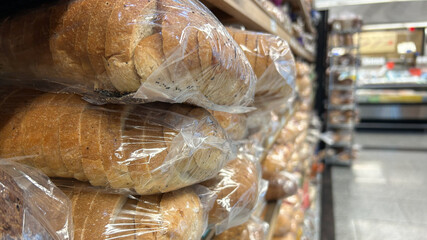 A close-up view of packaged loaves of bread stacked on a shelf in a grocery store