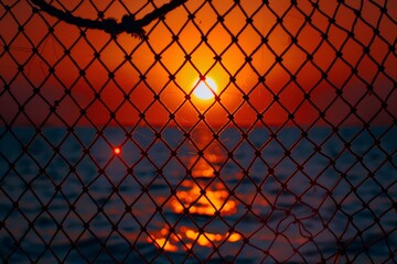 Sunset Over Ocean Through Chain Link Fence
