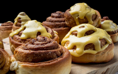 Golden-brown cinnamon rolls topped with rich, creamy glaze on a wooden board