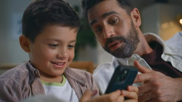 Man parent kid playing online smartphone game at evening apartment home closeup