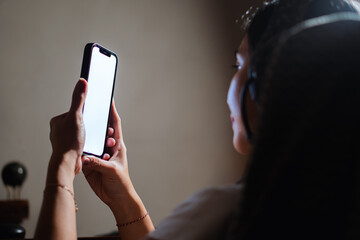 Person holding smart phone with blank screen in dimly lit room