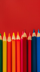 Row of multi-colored pencils on a pink, blue, red and yellow backgrounds