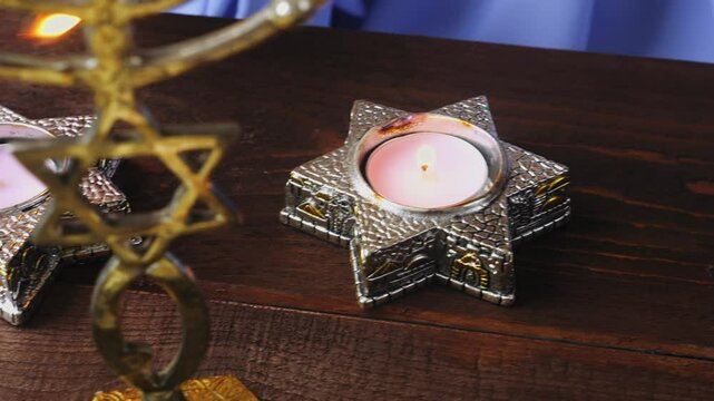 The hand of a Jewish woman lights candles on the Passover Seder holiday at a laid table