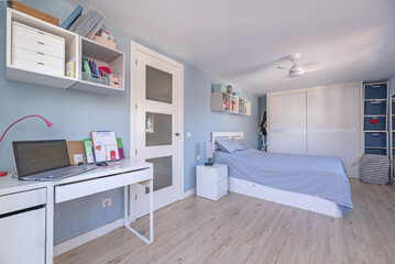 Bedroom with white furniture, desk, matching wardrobes and blue painted walls