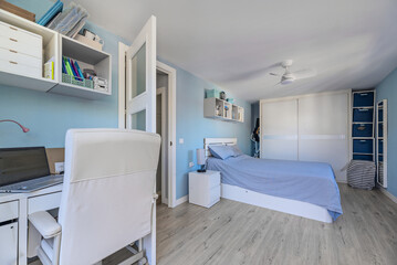 Bedroom with white furniture, desk with swivel chair, matching wardrobes and blue painted walls