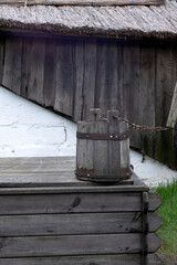 Obraz premium old wooden bucket of water hanging over the well with a wooden building