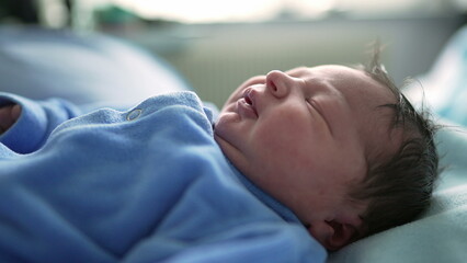 Newborn baby sleeping peacefully wearing blue onesie, close-up focus on the baby’s face. serene expression highlights the innocence and tranquility of a newborn’s restful sleep in early infancy