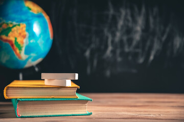 books, globe and white chalkboard crayons on the table on a black chalkboard. Education, September 1, new academic year