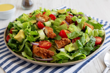 Homemade Crispy Chicken Salad with Tomato and Cucumber on a Plate, side view. Close-up.