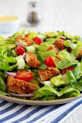 Homemade Crispy Chicken Salad with Tomato and Cucumber on a Plate, side view. Close-up.