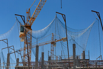 Edificio en construcción con redes de protección y grúa.