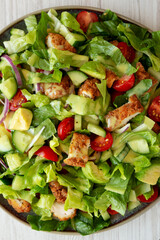 Homemade Crispy Chicken Salad with Tomato and Cucumber on a Plate, top view.