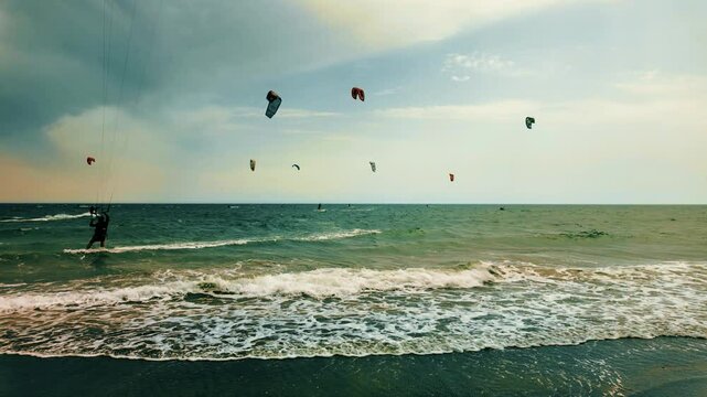 People surf with Kyte surfers on the sea waves in summer near people bathing. Extreme sports and outdoor life. Warm holiday with wind on the sea High speed and adrenaline. Strong wind